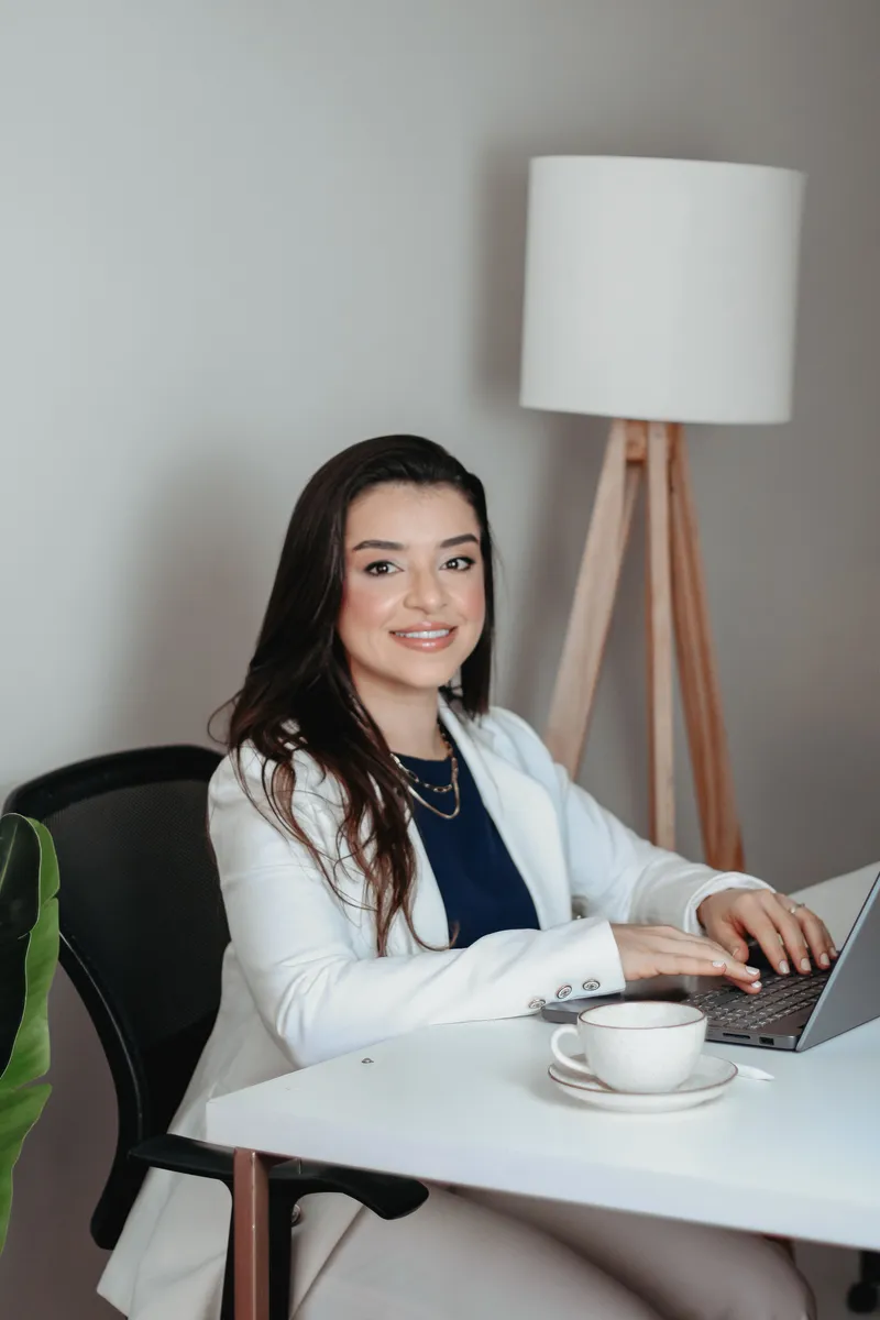 Dra. Luana Schauffer sorrindo em sua mesa de atendimento